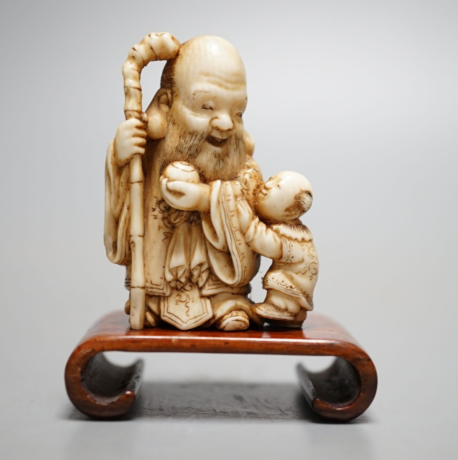 A Japanese ivory netsuke of Hotei and a boy, Meiji period, signed, 5 cms high.